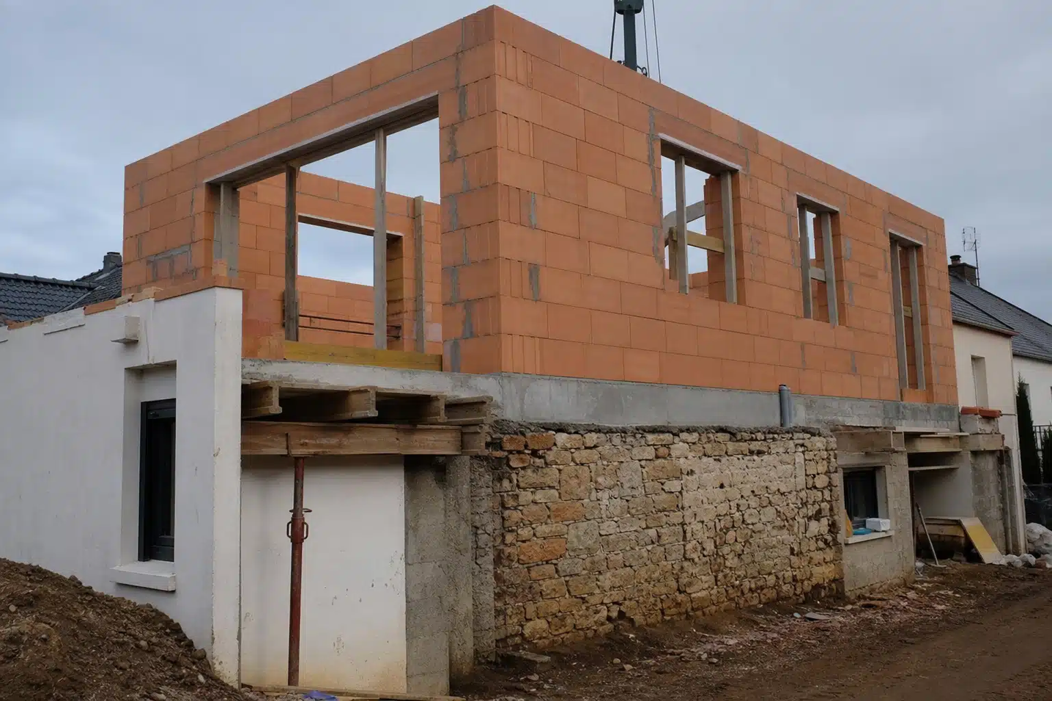 Maison en construction en briques avec soubassement en pierre